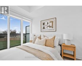 A bedroom with a large bed and a view of a backyard through a sliding glass door.