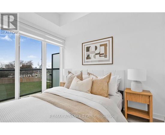 A bedroom with a large bed and a view of a backyard through a sliding glass door.