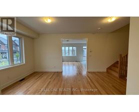 A spacious room with wooden flooring and a large window.