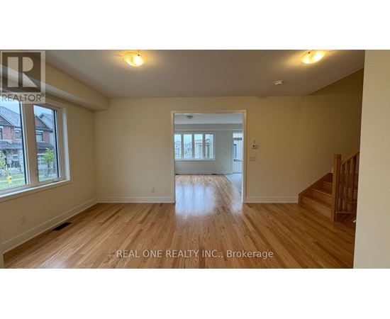 A spacious room with wooden flooring and a large window.