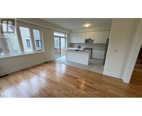 A spacious kitchen with white cabinets and a wooden floor.