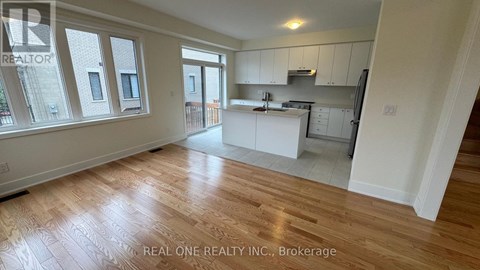 A spacious kitchen with white cabinets and a wooden floor.