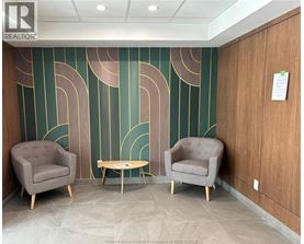 Two grey chairs and a table are in front of a green and gold wall.