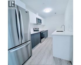 A modern kitchen with a refrigerator, microwave, and oven.
