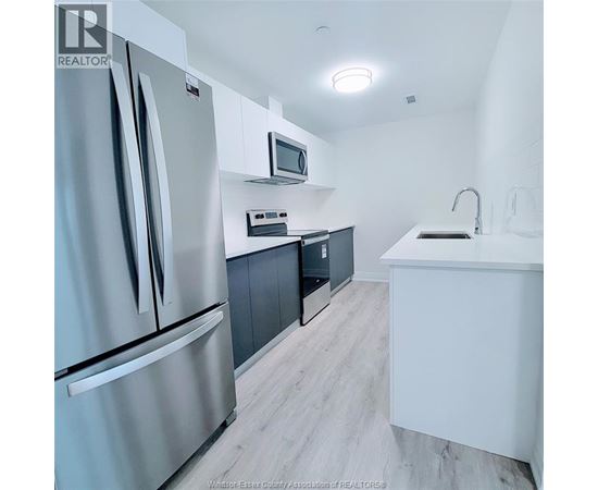 A modern kitchen with a refrigerator, microwave, and oven.