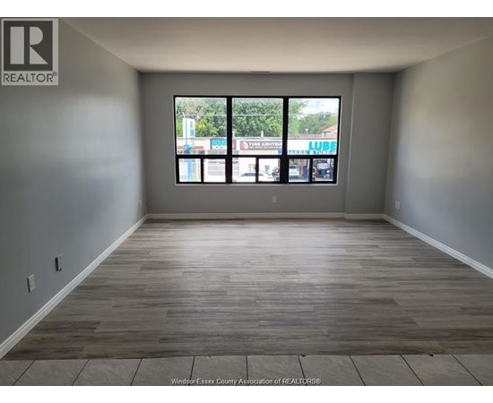 A room with a large window and wooden flooring.