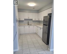 A kitchen with white cabinets and a black refrigerator.