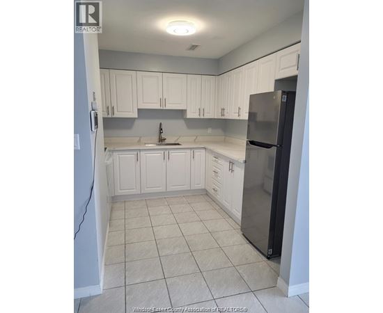 A kitchen with white cabinets and a black refrigerator.
