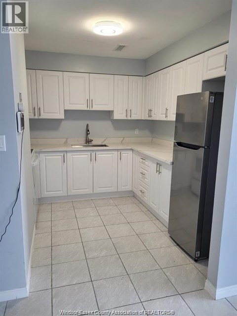 A kitchen with white cabinets and a black refrigerator.