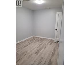 A room with a white door and grey flooring.