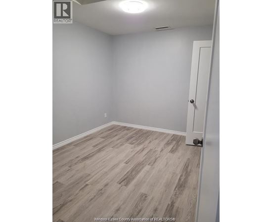 A room with a white door and grey flooring.