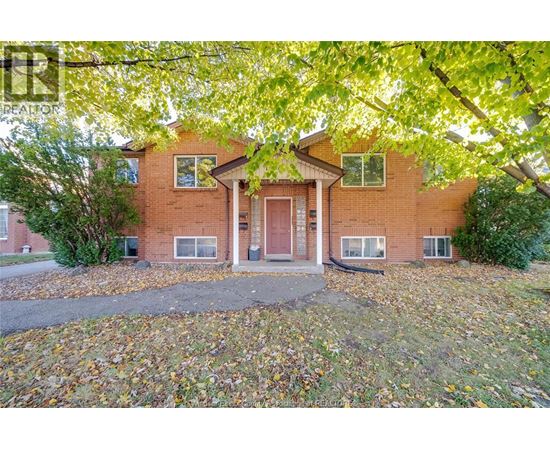 A house with a red door surrounded by trees and fallen leaves.