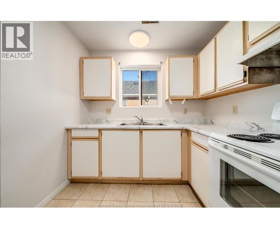 A kitchen with white cabinets and a white stove top oven.