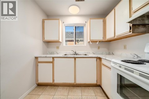 A kitchen with white cabinets and a white stove top oven.