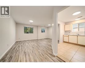 A spacious room with wooden flooring and a large window.