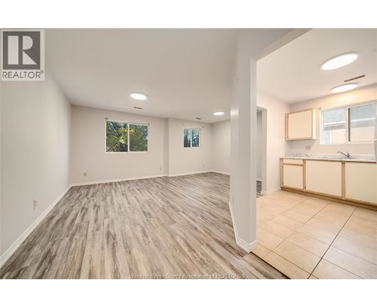 A spacious room with wooden flooring and a large window.