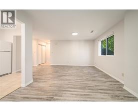 A spacious room with wooden flooring and white walls.
