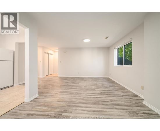 A spacious room with wooden flooring and white walls.