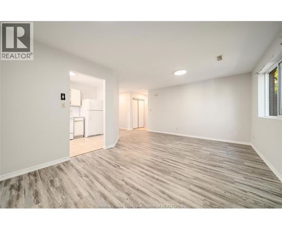 A spacious room with wooden flooring and white walls.