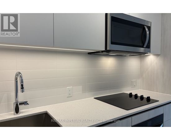 A modern kitchen with a black stove top and a silver faucet.