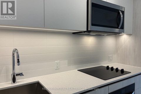A modern kitchen with a black stove top and a silver faucet.