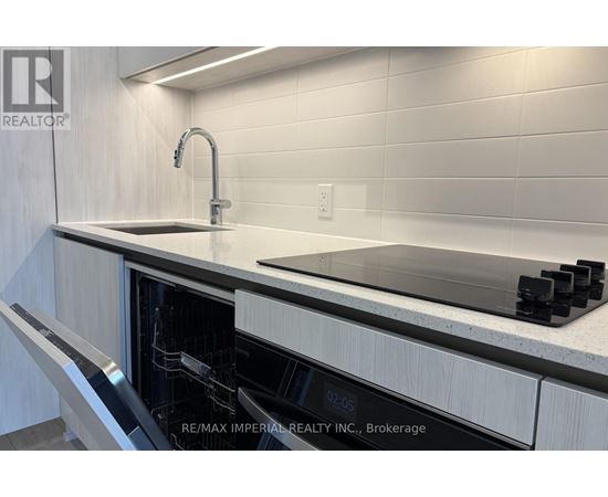 A modern kitchen with a sink and a digital clock showing 02:05.
