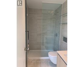 A glass shower stall in a bathroom with a white toilet.