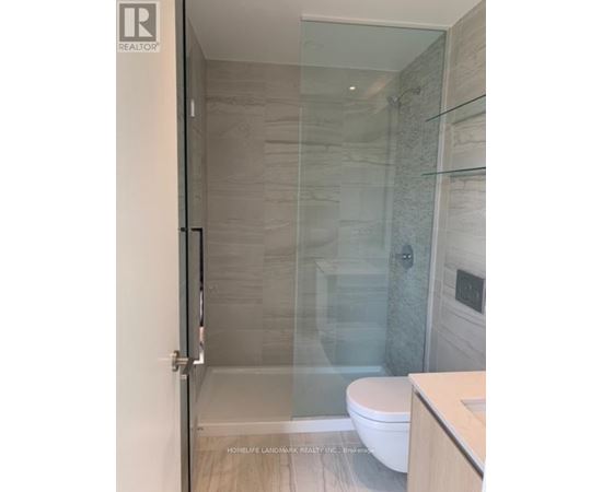 A glass shower stall in a bathroom with a white toilet.