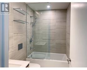 A bathroom with a glass shower door and a white tub.