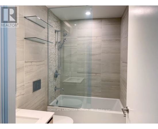 A bathroom with a glass shower door and a white tub.