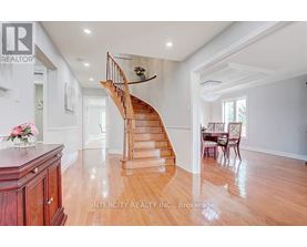 A wooden staircase in a spacious room with a dining table set up.