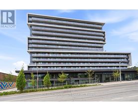 A modern multi-story building with a glass facade and a street view in front.