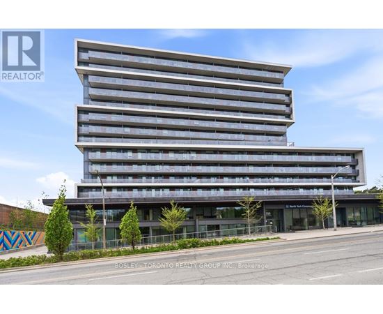 A modern multi-story building with a glass facade and a street view in front.