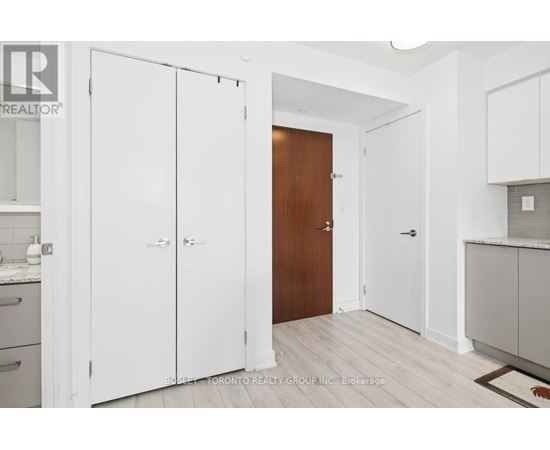 A kitchen with white cabinets and a wooden door.