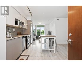 A modern kitchen with a dining area in the background.