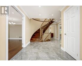 A spacious hallway with a marble floor and a wooden staircase.