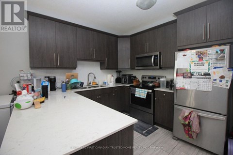 A kitchen with a white counter top and a refrigerator with a calendar on it.