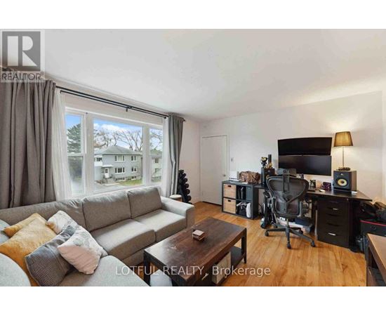 A living room with a grey couch, a coffee table, a television, and a desk with a chair.