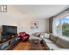 A living room with a grey couch, a red chair, and a flat screen TV.