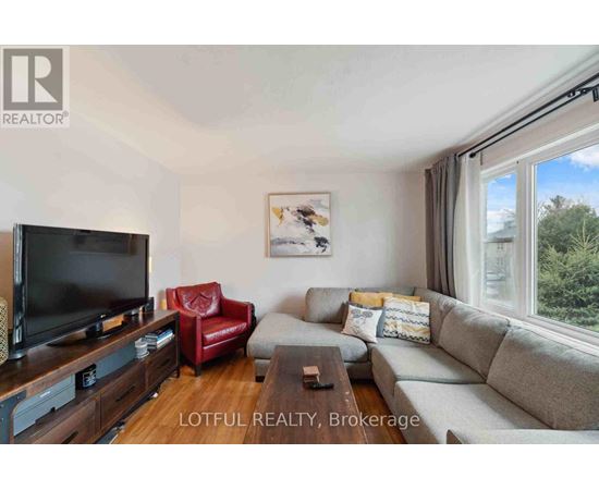 A living room with a grey couch, a red chair, and a flat screen TV.