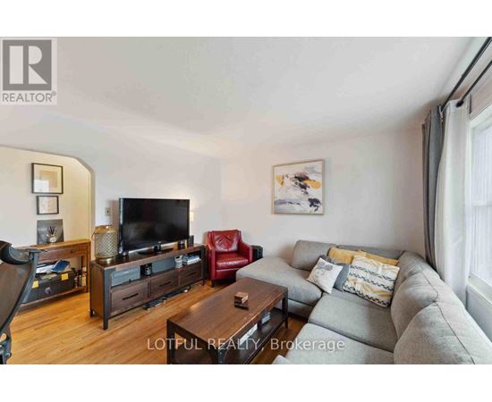 A living room with a grey couch, a red chair, a wooden coffee table, and a television.