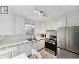 A white kitchen with a refrigerator, sink, and oven.