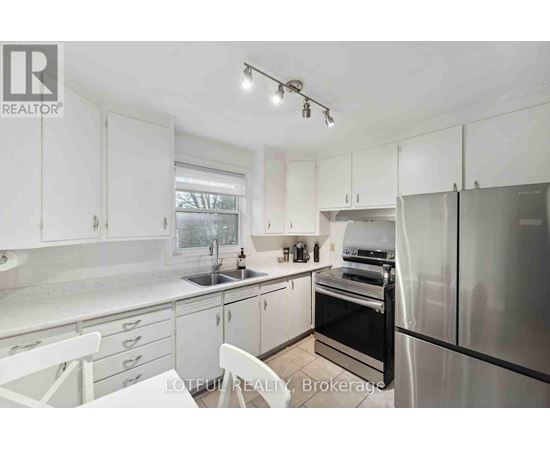 A white kitchen with a refrigerator, sink, and oven.