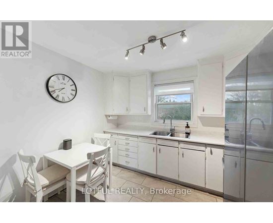 A white kitchen with a table and chairs and a clock on the wall.