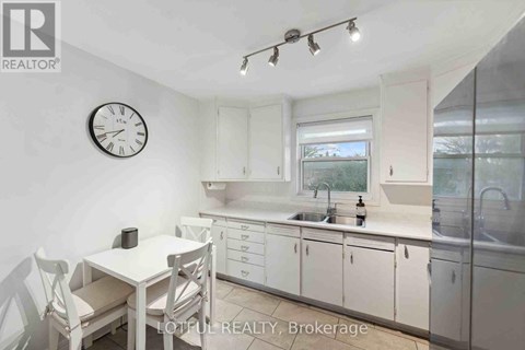 A white kitchen with a table and chairs and a clock on the wall.