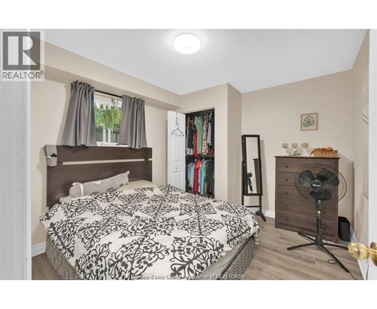 A bedroom with a large bed and a wooden chest of drawers.