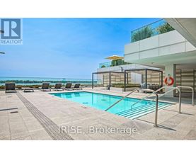 A pool area with a glass wall overlooking the ocean.