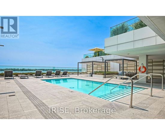 A pool area with a glass wall overlooking the ocean.