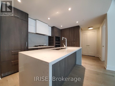 A modern kitchen with dark wood cabinets and a white island.