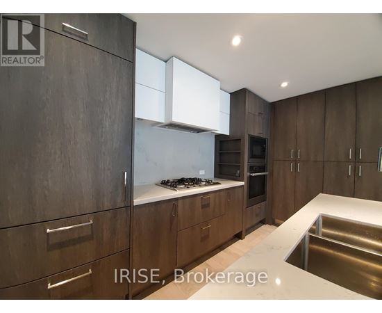 A modern kitchen with dark wood cabinets and stainless steel appliances.